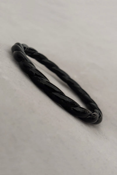 Vertical perspective view of 1980s vintage black plastic twisted, ridged, and orange goldfish painted bangle bracelet set of three (3). Showing the twisted rope bangle only.