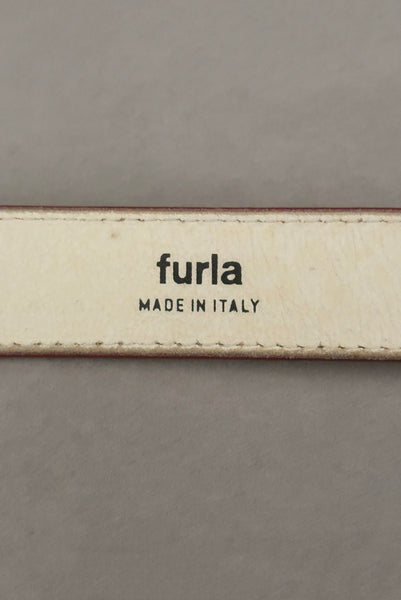 Interior detail view of 1980s vintage designer red stamped Italian leather belt  with brass buckle by Furla, size medium to large. Made in Italy. Showing a close-up of the Furla and Made in Italy stamps.