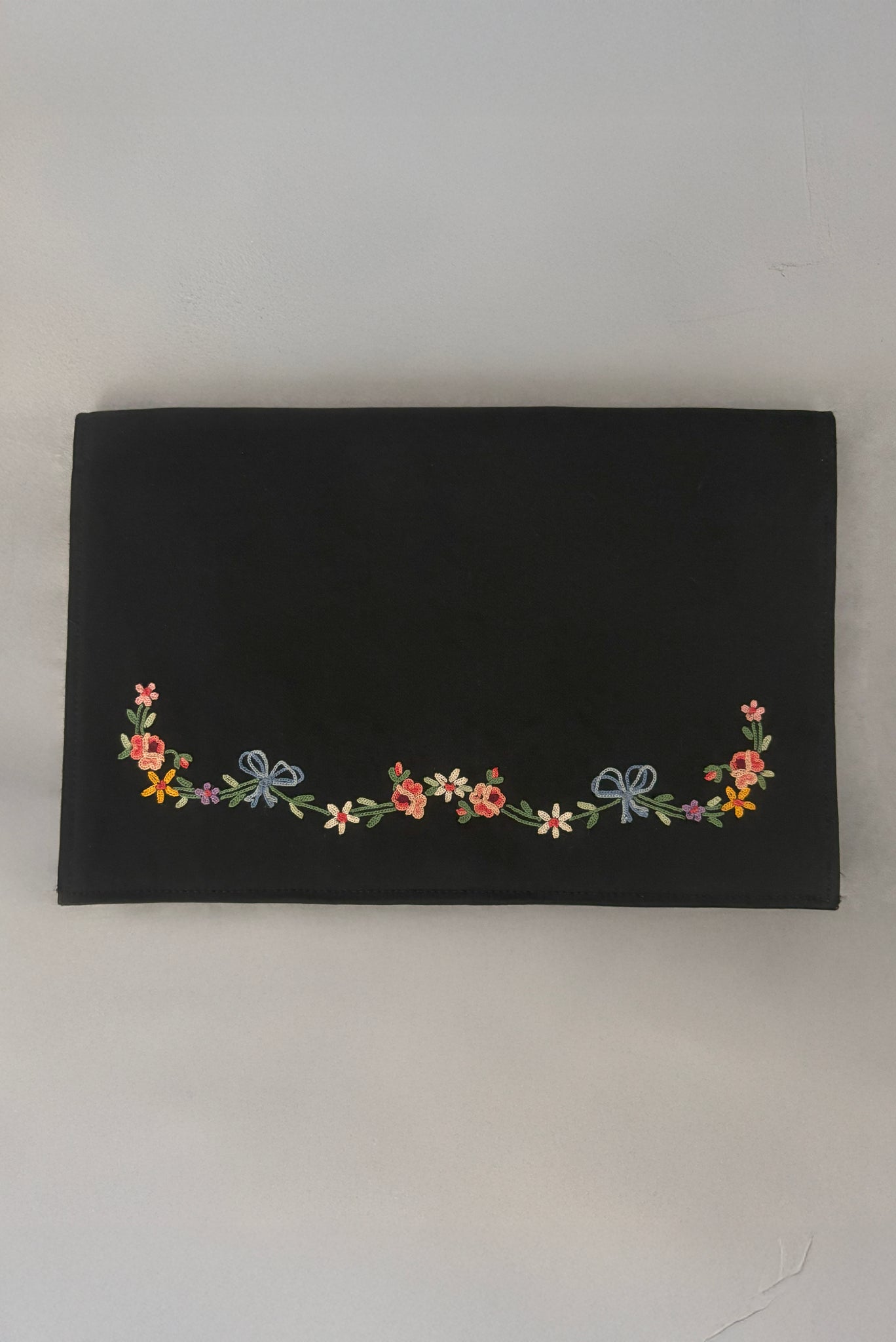 Vertical front view of 1930s vintage black satin clutch with pink, blue, green, purple, and gold floral chainstitch embroidered clutch by Denis Francet.