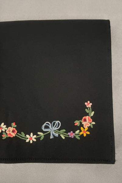 Detail view of 1930s vintage black satin clutch with pink, blue, green, purple, and gold floral chainstitch embroidered clutch by Denis Francet. Showing  a close-up of the flower and bow embroidery.
