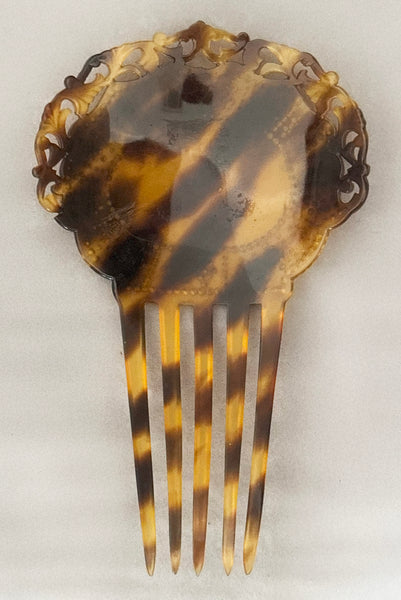 Vertical back view of 1920s vintage early plastic marbled brown tortoise hair comb with clear, red, and blue rhinestones.