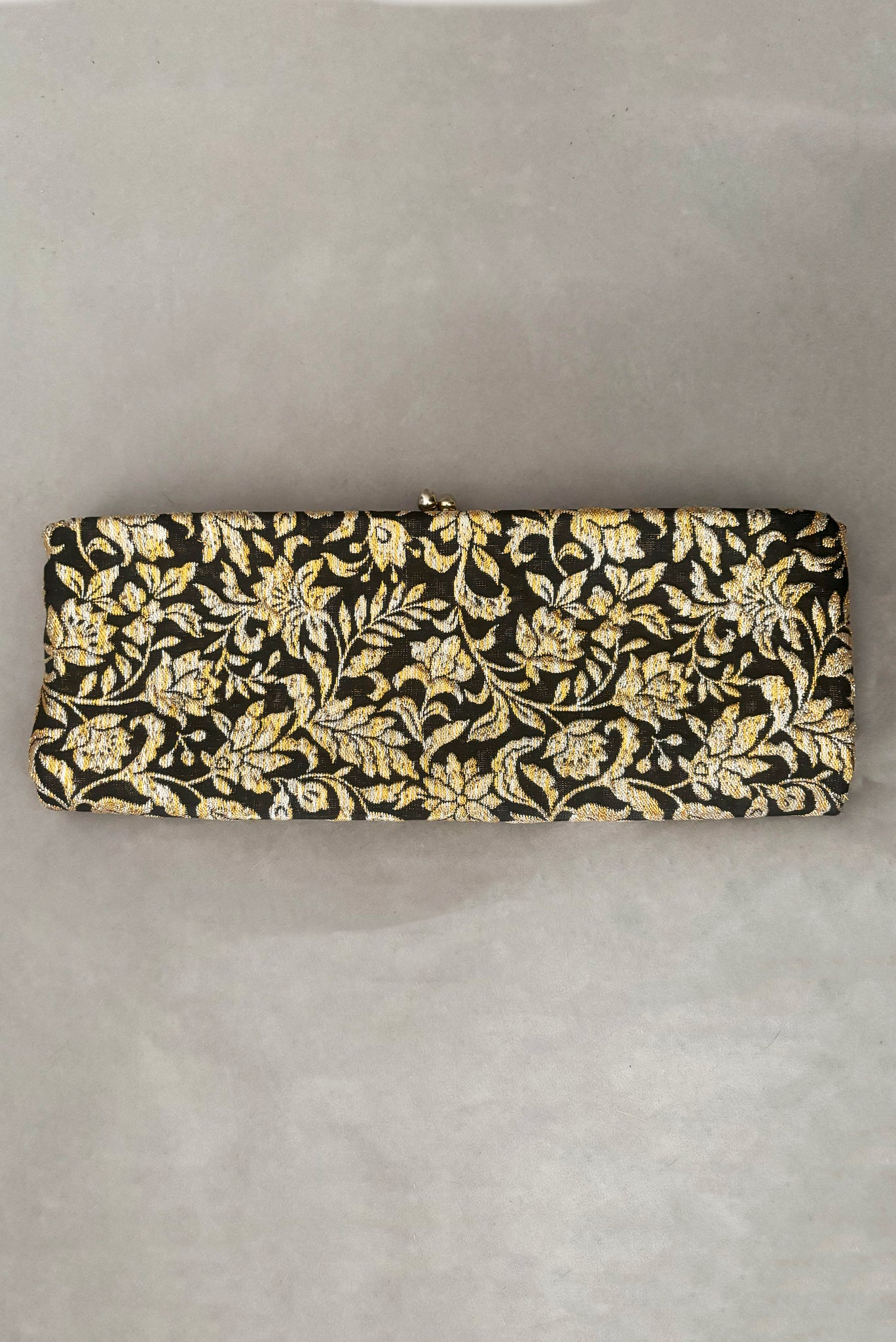 Vertical front view of 1960s vintage black, gold, and silver metallic floral brocade long evening clutch purse with foldout chain handle.