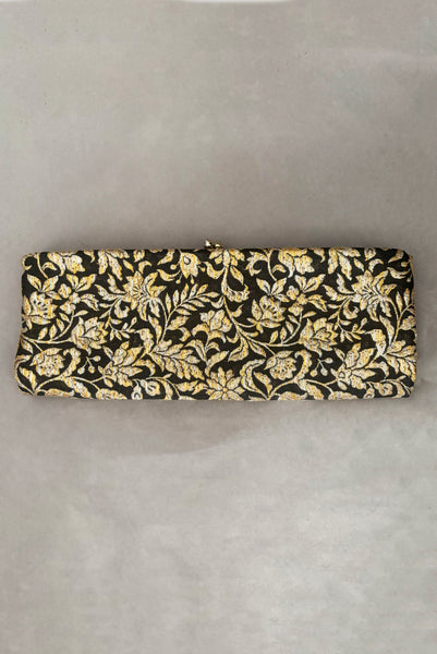 Vertical front view of 1960s vintage black, gold, and silver metallic floral brocade long evening clutch purse with foldout chain handle.