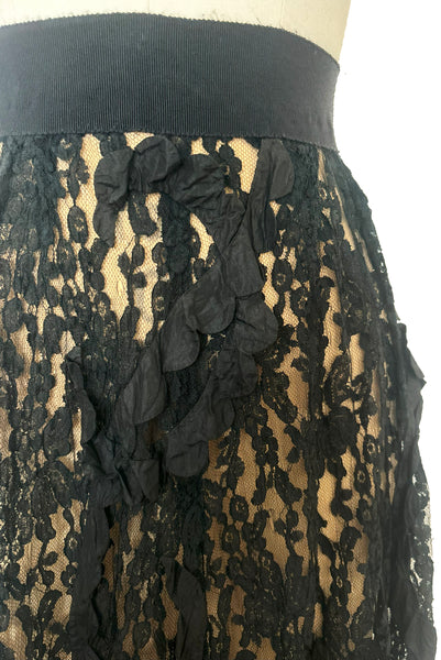 Front detail view of 1990s vintage goth sheer black lace and taffeta nude look skirt, medium to large. Showing the black silk taffeta scalloped swirls on the embellished lace, and small breaks in the lace netting.
