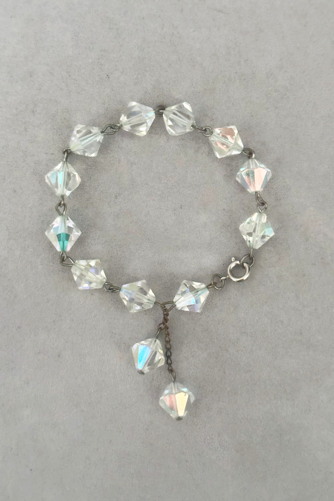 Vertical closed view of 1960s vintage iridescent crystal bicone bead and silver tone bracelet.
