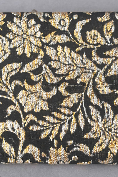 Back detail view of 1960s vintage black, gold, and silver metallic floral brocade long evening clutch purse with foldout chain handle. Showing a snag or pulled thread in the brocade fabric.