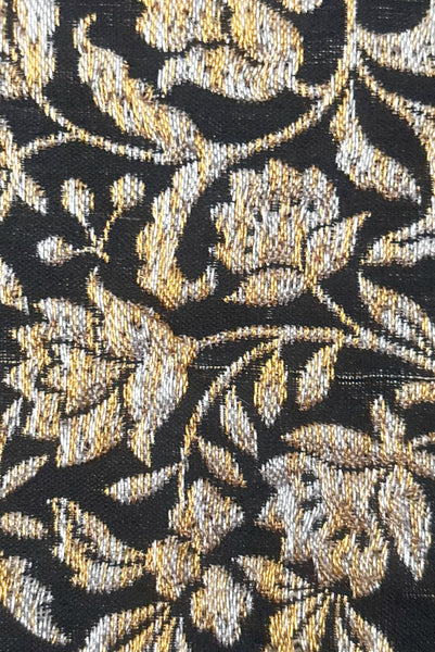 Back detail view of 1960s vintage black, gold, and silver metallic floral brocade long evening clutch purse with foldout chain handle. Showing a snag or pulled thread in the brocade fabric.