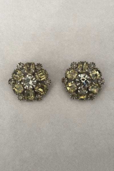 Vertical front view of 1950s vintage smoke gray rhinestone and silver tone metal round clip-on earrings by Weiss.