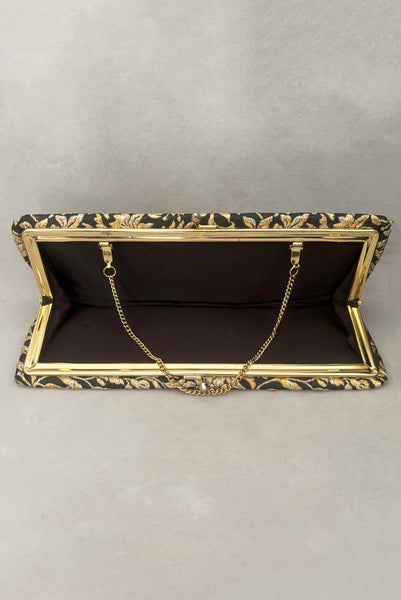 Vertical interior view of 1960s vintage black, gold, and silver metallic floral brocade long evening clutch purse with foldout chain handle. Showing the interior with its black synthetic lining.