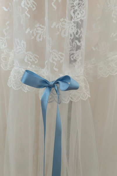 Detail view of 1980s vintage sheer white lace & tulle skirt with train, trimmed with blue satin ribbon bows, small, medium, large. Showing the lace trim and blue ribbon bows.