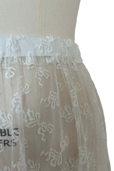 Detail view of 1980s vintage sheer white lace & tulle skirt with train, trimmed with blue satin ribbon bows, small, medium, large. Showing the elastic waist.