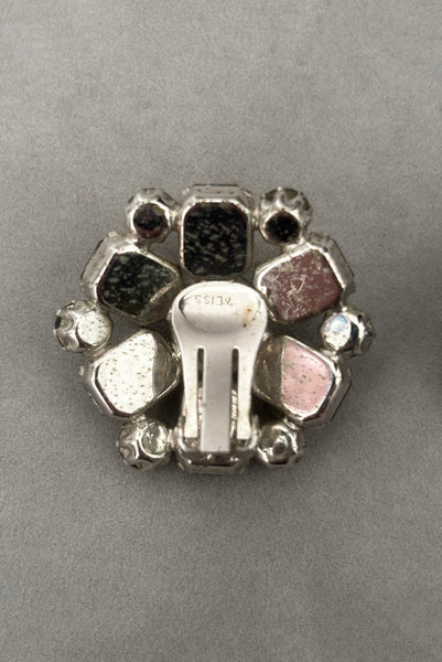 Detail view of 1950s vintage smoke gray rhinestone and silver tone metal round clip-on earrings by Weiss. Showing the Weiss stamp.