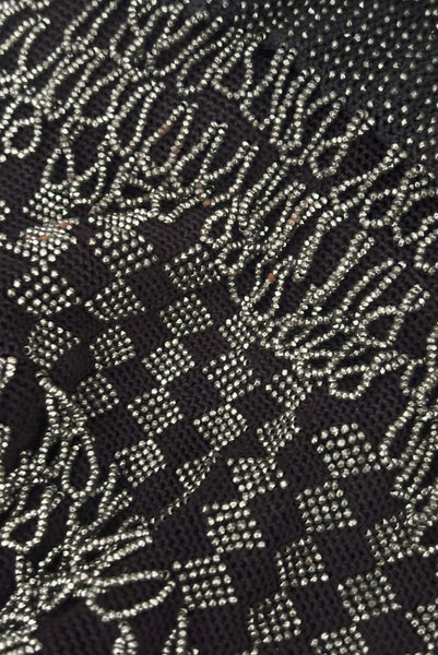 Detail view of 1910s turn of the century vintage Edwardian silver gray beaded black crochet drawstring handbag. Showing a close-up of the checkerboard and fringe beading.