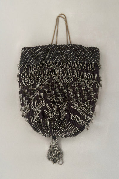 Vertical front view of 1910s turn of the century vintage Edwardian silver gray beaded black crochet drawstring handbag.