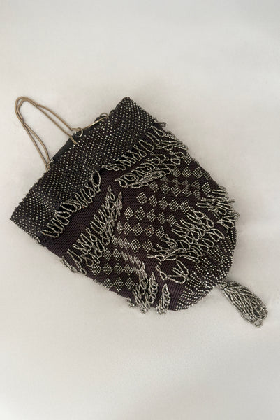 Vertical back view of 1910s turn of the century vintage Edwardian silver gray beaded black crochet drawstring handbag.