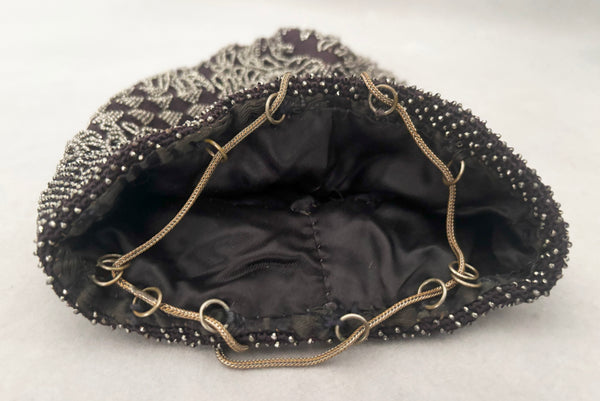 Detail view of 1910s turn of the century vintage Edwardian silver gray beaded black crochet drawstring handbag. Showing the loops and metal cording that create the drawstring closure.