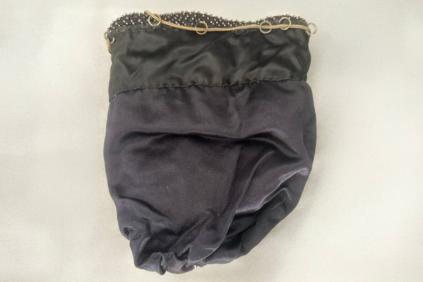 Horizontal interior view of 1910s turn of the century vintage Edwardian silver gray beaded black crochet drawstring handbag. Showing the satin lining.