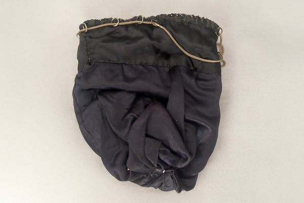 Horizontal interior view of 1910s turn of the century vintage Edwardian silver gray beaded black crochet drawstring handbag. Showing the satin lining.