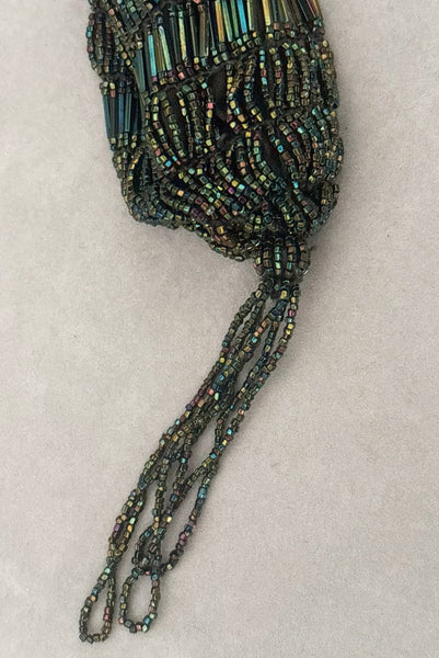 Detail view of 1910s turn of the century vintage Edwardian black peacock iridescent glass beaded drawstring handbag. Showing a close-up of the iridescent beaded tassel.
