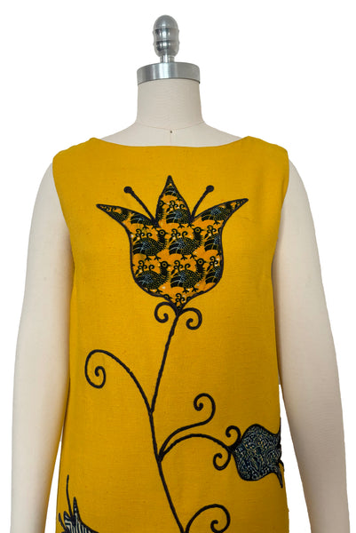 Bodice front view of 1960s vintage mustard yellow silk suiting shift dress with navy blue, white, & yellow tulip appliques and embroidery by Crazy Horse, small to medium. Showing a large tulip applique in a bird print.