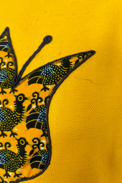 Bodice detail view of 1960s vintage mustard yellow silk suiting shift dress with navy blue, white, & yellow tulip appliques and embroidery by Crazy Horse, small to medium. Showing a mark next to the largest applique.