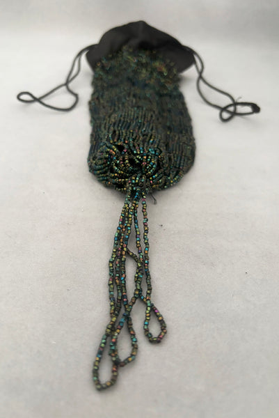 Vertical bottom view of 1910s turn of the century vintage Edwardian black peacock iridescent glass beaded drawstring handbag. Showing the iridescent beaded tassel.