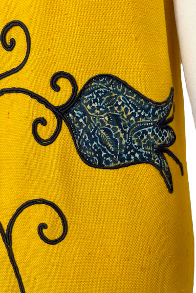 Front detail view of 1960s vintage mustard yellow silk suiting shift dress with navy blue, white, & yellow tulip appliques and embroidery by Crazy Horse, small to medium. Showing a tulip applique in a floral print.