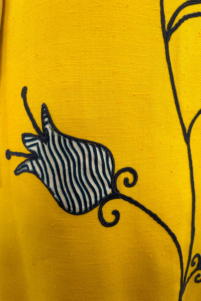 Front detail view of 1960s vintage mustard yellow silk suiting shift dress with navy blue, white, & yellow tulip appliques and embroidery by Crazy Horse, small to medium. Showing a tulip applique in a wavy stripe print.