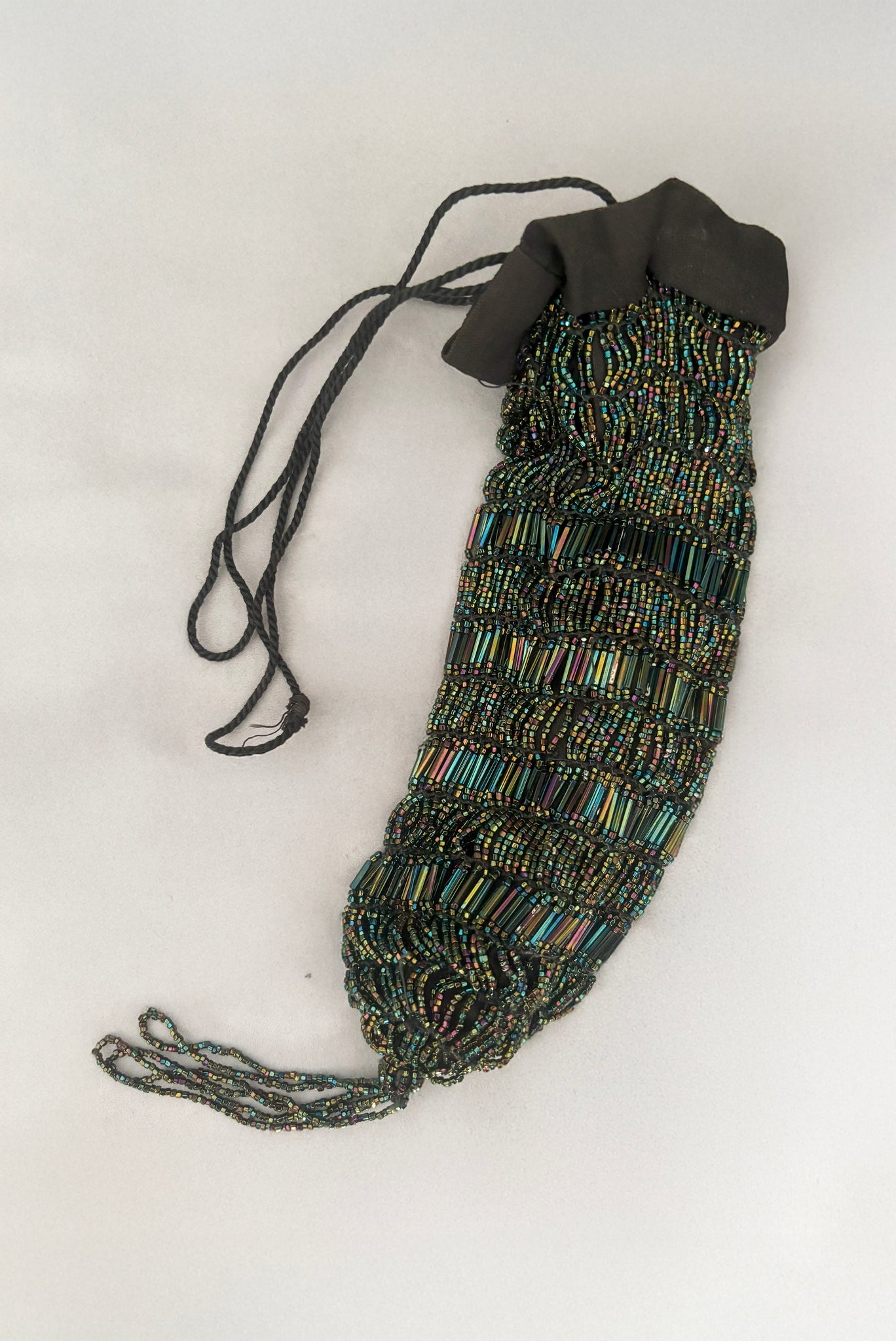 Vertical view of 1910s turn of the century vintage Edwardian black peacock iridescent glass beaded drawstring handbag.