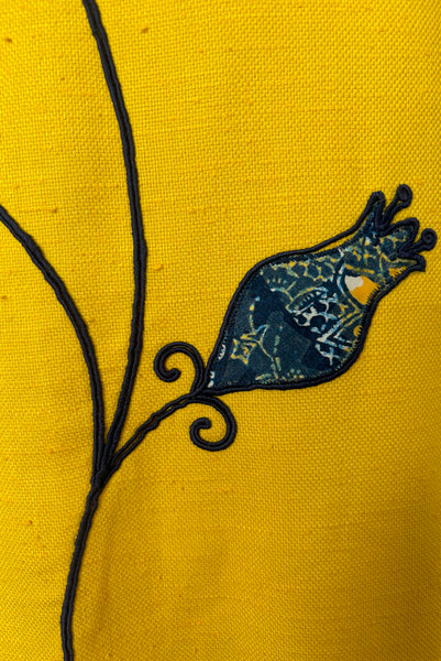 Front detail view of 1960s vintage mustard yellow silk suiting shift dress with navy blue, white, & yellow tulip appliques and embroidery by Crazy Horse, small to medium. Showing a tulip applique in a batik print.