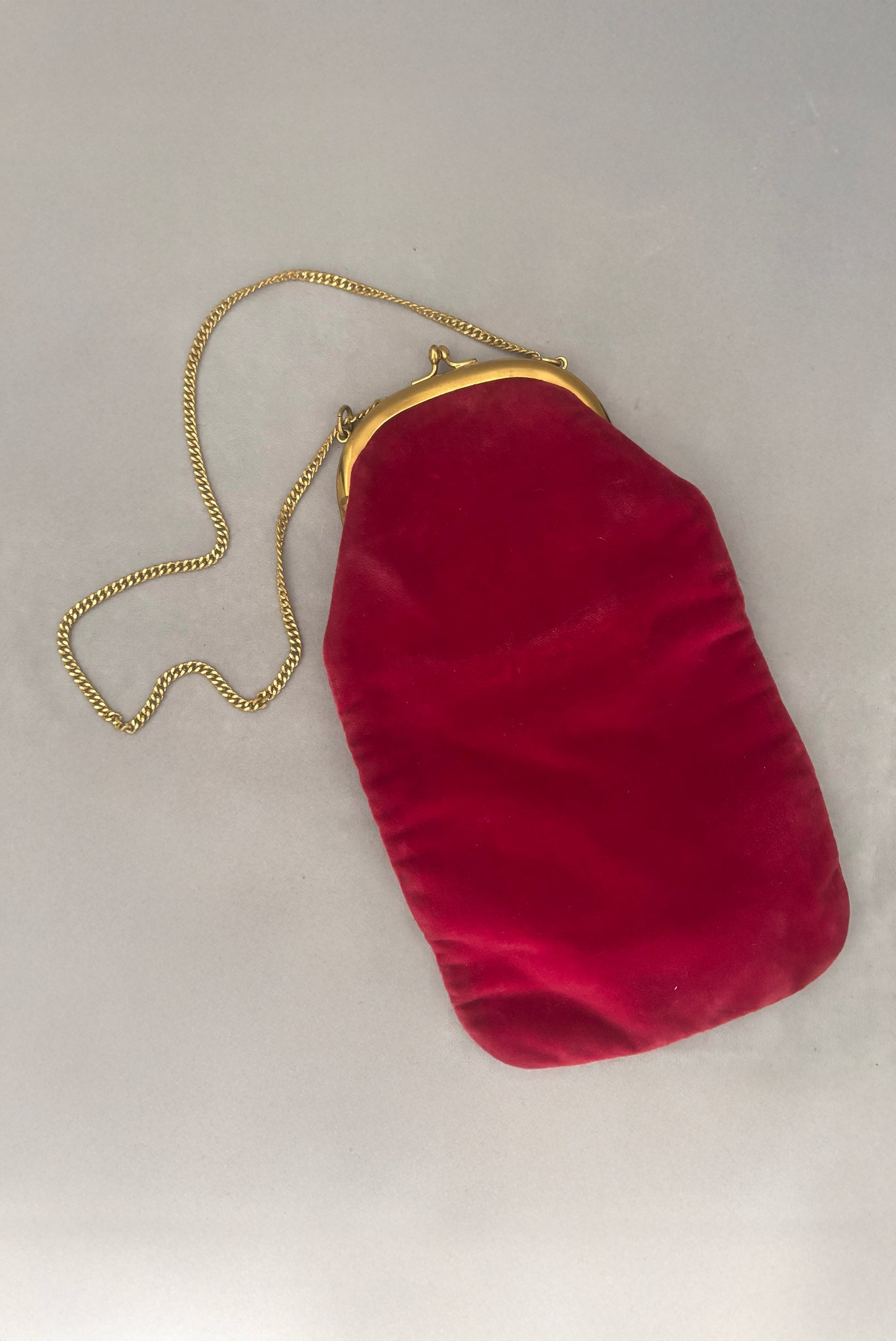 Vertical styled view of 1960s vintage rose pink velvet evening handbag with gold frame and chain handle, by Morris Moskowitz.