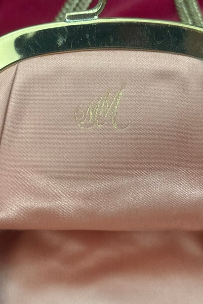 Detail view of 1960s vintage rose pink velvet evening handbag with gold frame and chain handle, by Morris Moskowitz. Showing the peach satin lining and gold MM stamp.