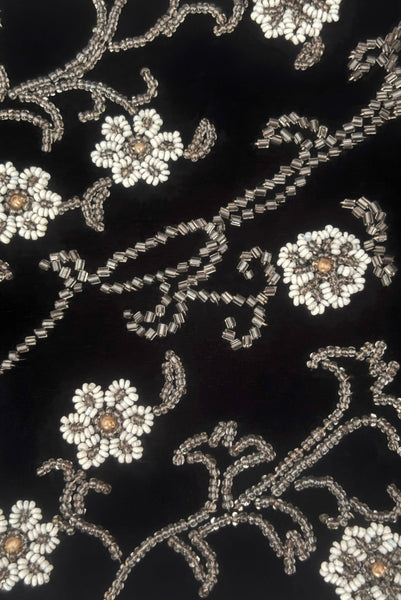 Detail view of 1950s vintage black velvet floral silver and white glass and faux cream pearl beaded clutch evening bag. Showing a close-up of the beading on the front including the wear to the finish of the faux pearl beads.