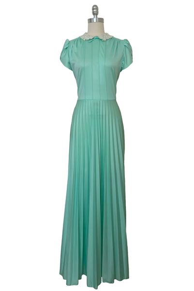 Front view of 1970s vintage mint green knit maxi dress with lace peter pan collar, tulip sleeves, pintucked bodice, and pleated skirt, small to medium.
