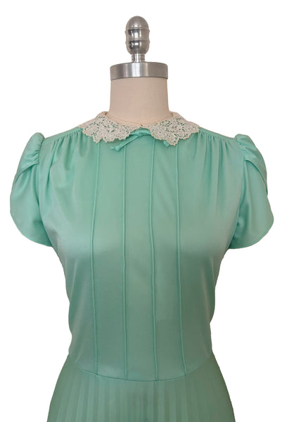 Bodice front view of 1970s vintage mint green knit maxi dress small to medium. Showing the re embroidered cream lace peter pan collar with bow, tulip sleeves, gathered shoulders, and pintucked bodice.