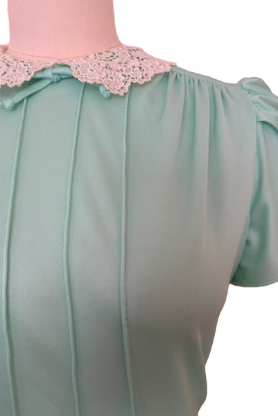 Bodice detail view of 1970s vintage mint green knit maxi dress small to medium. Showing the re embroidered cream lace peter pan collar with bow, tulip sleeves, gathered shoulders, and pintucked bodice.