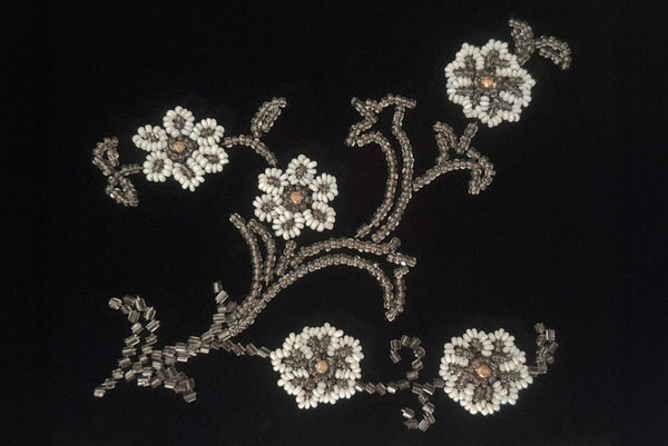 Detail view of 1950s vintage black velvet floral silver and white glass and faux cream pearl beaded clutch evening bag. Showing a close-up of the beading on the back including the wear to the finish of the faux pearl beads.