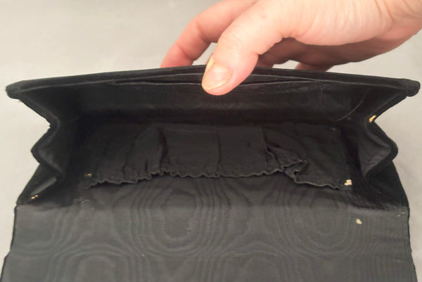 Detail view of 1950s vintage black velvet floral silver and white glass and faux cream pearl beaded clutch evening bag. Showing a close-up the lining with a small hole, and wear to the edges.