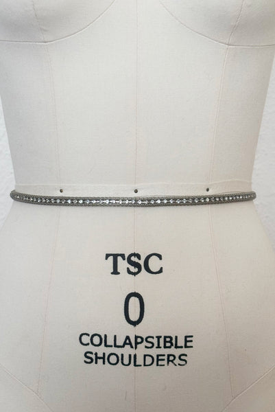 Vertical back view of 1960s vintage adjustable silver tone metal mesh and rhinestone chain belt with floral hook, size medium to large.