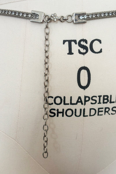 Detail view of 1960s vintage adjustable silver tone metal mesh and rhinestone chain belt with floral hook, size medium to large. Showing the adjustable chain and silver tone rhinestone floral hook closure.