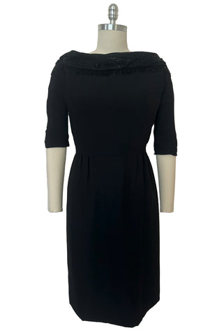 Front view of 1960s vintage black fringe beaded and sequin boat neckline with standing collar cocktail dress by Elissa of California, medium to large. With V back, elbow length sleeves and pencil skirt.