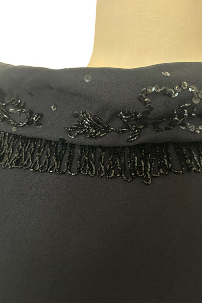 Bodice front detail view of 1960s vintage black fringe beaded and sequin boat neckline with standing collar cocktail dress by Elissa of California, medium to large. Showing the beaded fringe, and floral sequin collar.
