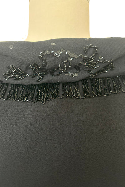 Bodice front detail view of 1960s vintage black fringe beaded and sequin boat neckline with standing collar cocktail dress by Elissa of California, medium to large. Showing the beaded fringe, and floral sequin collar.
