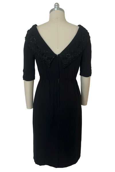 Back view of 1960s vintage black fringe beaded and sequin boat neckline with standing collar cocktail dress by Elissa of California, medium to large. With V back, elbow length sleeves and pencil skirt.