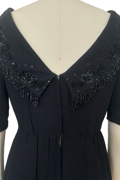 Bodice back view of 1960s vintage black fringe beaded and sequin boat neckline with standing collar cocktail dress by Elissa of California, medium to large. With V back, elbow length sleeves and pencil skirt.