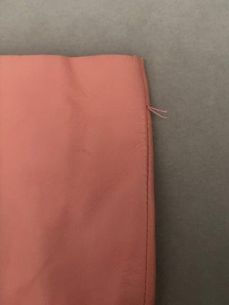 Detail view of 2000s y2k vintage pink leather unlined opera gloves with snap wrists, by J.Crew, size L. Showing part of the thread tack that once joined them together.