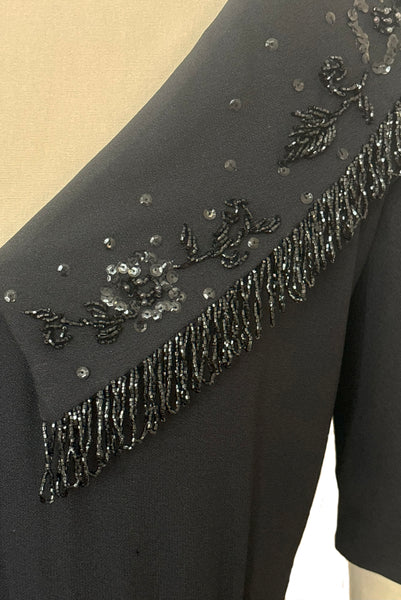 Bodice back detail view of 1960s vintage black fringe beaded and sequin boat neckline with standing collar cocktail dress by Elissa of California, medium to large. Showing the beaded fringe, and floral sequin collar.