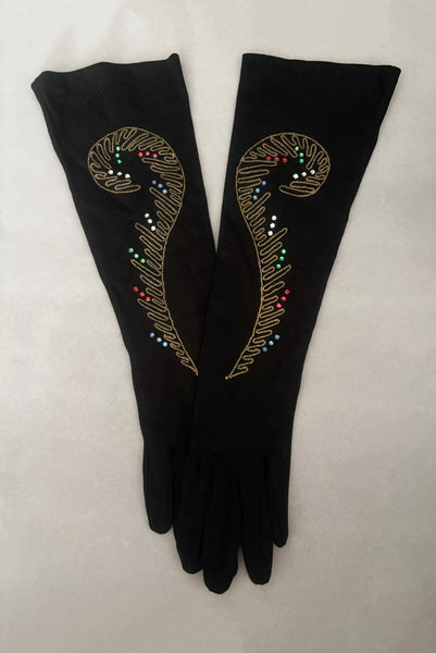 Vertical pair view of 1950s vintage black mid length gloves with clear, red, blue, & green prong set rhinestone and gold work embroidery by Lady Gay, size 7.