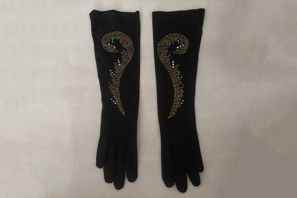 Horizontal front view of 1950s vintage black mid length gloves with clear, red, blue, & green prong set rhinestone and gold work embroidery by Lady Gay, size 7.