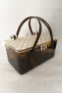 Vertical perspective view of 1950s vintage tortoiseshell brown marbled Lucite box bag with clear faceted lid.